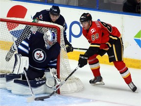 Calgary Flames prospect Pavel Karnaukhov tries to put puck past Winnipeg Jets goaltender Connor Hellebuyck as Jets' Matteo Gennaro defends during the YoungStars Classic showcase in Penticton, B.C. earlier this month.