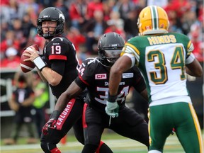 Calgary Stampeders quarterback Bo Levi Mitchell has  running back Tory Harrison holding off Eskimos safety Ryan Hinds during Monday's Labour Day Classic at McMahon Stadium