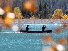 Surrounded by fall colours, a couple of canoers paddle around the point of the Spray reservoir above Canmore on Wednesday, Sept. 23.