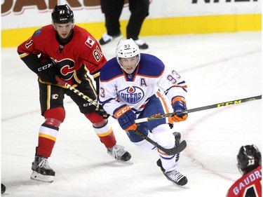 Calgary Flames defenceman Brett Kulak, left, checked Edmonton Oilers centre Ryan Nugent-Hopkins during the first period of a split squad preseason NHL game at the Scotiabank Saddledome on September 21, 2015.