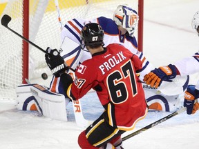 Calgary Flames right winger Michael Frolik shoots the puck past Edmonton Oilers goalie Ben Scrivens during the second period of a split squad preseason NHL game at the Scotiabank Saddledome.