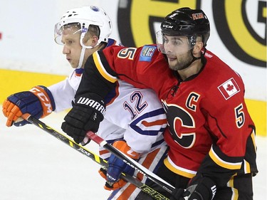 Calgary Flames defenceman Mark Giordano tied up Edmonton Oilers left winger Rob Klinkhammer during the second period of a split squad preseason NHL game at the Scotiabank Saddledome on September 21, 2015.