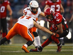 B.C. Lions' Adam Bighill, centre, and Eric Fraser, left, tackle Calgary Stampeders' Eric Rogers during first quarter CFL football action in Calgary, Friday, Sept. 18, 2015.