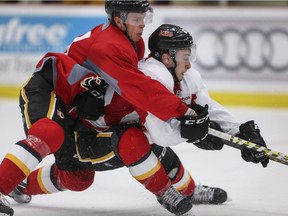 Brett Kulak, left, and Andrew Mangiapane get tangled in front of the net during a Flames scrimmage game at WinSport on Saturday. Camp gets kicked up a notch with Monday's preseason opener against the Edmonton Oilers.