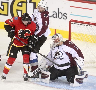 Calgary Flames Paul Byron, left, collides with  Colorado Avalanche Nick Holden, middle as he tries to score on Avalanche net minder Calvin Pickard during pre-season action at the Scotiabank Saddledome.