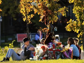 Friends of Nick Paswisty gather around a large memorial to the teen on Sunday evening near the location where he was struck and killed by an SUV while crossing Erinwoods Blvd. on Friday morning.