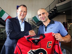 Calgary Flames captain Mark Giordano, right, and GM Brad Treliving pose with a jersey at the Calgary Italian Open Charity Golf Tournament at The Hamptons Golf Club on Wednesday.