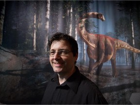 Natural history illustrator Julius Csotonyi stands for a photograph with one of his dinosaur illustrations on display.