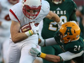 U of C Dinos running back Mercer Timmis breaks a tackle and heads for daylight as Alberta's Ryan Migadel attempts to slow him down on Thursday night. There was no slowing down the Dinos, who scored 80 points.