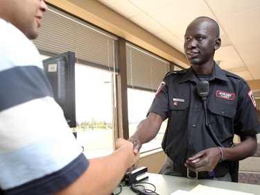 Stephen Deng shakes hands with a man at the Calgary Police District 3 detachment Wednesday July 15, 2015. The former Sudanese refugee recently graduated from the Calgary Police Auxilliary Cadet Program and now works at the detachment on front desk duties.