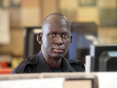 Stephen Deng looks up from his desk at the Calgary Police District 3 detachment Wednesday July 15, 2015. The former Sudanese refugee recently graduated from the Calgary Police Auxilliary Cadet Program and now works at the detachment on front desk duties.
