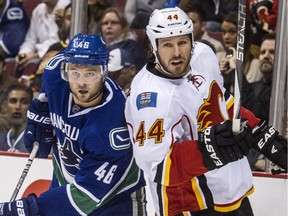 Calgary Flames' hopeful Ryan Wilson keeps Vancouver's Niklas Jensen   in check during Saturday's NHL pre-season game. Wilson survived the latest round of cuts and appears to be one of four blueliners left to compete for two openings.