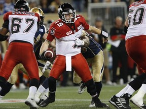 Calgary Stampeders quarterback Bo Levi Mitchell (19) tries to break free of Winnipeg Blue Bombers' Jamaal Westerman (55) during the first half of CFL action in Winnipeg Friday, September 25, 2015.