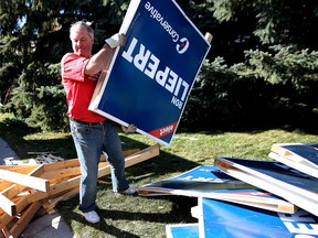 Former Alberta cabinet minister Ron Liepert cleans up his signs in Calgary a day after his victory in Signal Hill.