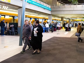 Passengers check in at the WestJet counter at the Calgary International Airport in Calgary on Friday, Oct. 23, 2015. WestJet cancelled flight WS2312 to Puerto Vallarta, Mexico, as Hurricane Patricia approached the resort community.