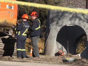 Occupational Health and Safety investigators study the scene of a fatal outdoor workplace accident on Rosehill Drive NW at 10th Street Friday afternoon, Oct. 23, 2015.