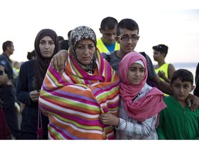 A Syrian family walks after they arrived with other refugees from Turkey to the shores of the Greek island of Lesbos, on an inflatable dinghy. Canada must properly vet the refugees to protect its own security, says the Herald editorial board.