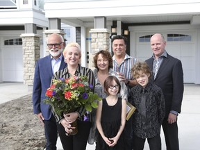 Shauna Hartwick and her two children, Teagan, 8, and Jacob, 10, move into their new home, welcomed by David Watson of Attainable Homes, left, and Warren Saunders, vice-president of sales and marketing for Mattamy Homes, right. At back Shauna's parents Carol and Don Hartwick.