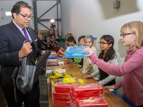 Mayor Naheed Nenshi gets help filling a backpack from Rundle College Elementary School volunteer Sarah Harley, 11,  with School Supplies for Kids, on Oct. 25, 2015.