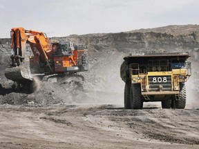 A haul truck carrying a full load drives away from a mining shovel at the Shell Albian Sands oilsands mine near Fort McMurray in this file photo.
