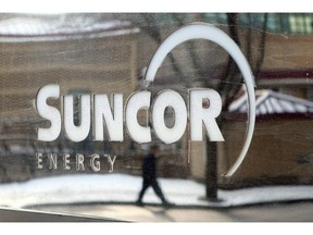 A pedestrian is reflected in a Suncor Energy sign in Calgary, Feb. 1, 2010.