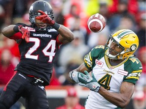 Edmonton Eskimos' Adarius Bowman, right, juggles a pass as Calgary Stampeders' Joe Burnett looks on during second half CFL football action in Calgary, Monday, September 7, 2015.