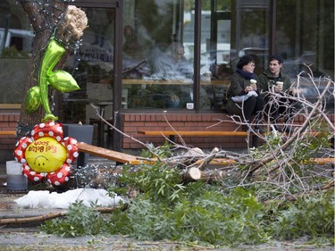 A "Feel Better Soon" balloon hangs from one of the trees fallen victim to the heavy, wet snow, in front of a coffee shop where Kelly Pleau, left, and Keaton Pridham sit.