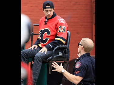 Calgary Flames forward Johnny Gaudreau gets a few official driving tips from a Calgary police service officer before driving a Zamboni down Centre Street and Stephen Avenue Mall in downtown Calgary on Tuesday. The event was part of a promotion with Sport Chek to kick off the start of regular season hockey.