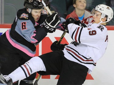 Calgary Hitmen Colby Harmsworth checks the Red Deer Rebels' Lane Pederson during WHL action at the Scotiabank Saddledome on Friday Oct. 9, 2015.