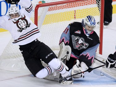 Red Deer Rebels' Ivan Nikolishin falls over Calgary Hitmen goaltender Lasse Peterson during WHL action at the Scotiabank Saddledome on Friday Oct. 9, 2015.