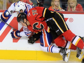 The Edmonton Oilers' Lauri Korpikoski  is checked by Calgary Flames forward Micheal Ferland during the second period of NHL action at the Scotiabank Saddledome Saturday October 17, 2015.
