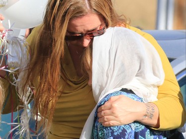 Supporters hug at the Withrow Gospel Mission prior to a balloon release in memory of the three Bott sisters; Catie, 13, Dara, 11, and Jana, 11,  who died in a tragic farm accident earlier in the week.