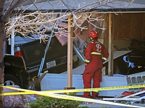 A firefighter checks the scene where a pick-up truck lost control and crashed through two garages on Cranston Drive, Wednesday afternoon. Police believe the driver who was deceased at the scene was suffering from some type of medical distress which led to the crash.