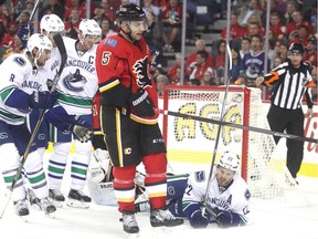 Calgary Flames captain Mark Giordano skates off as the Vancouver Canucks celebrate a late second period goal during the season opener on Wednesday at the Scotiabank Saddledome. Celebrating for the Canucks are, from left, Christopher Tanev, Brandon Sutter, Henrik Sedin and, on the ice, Daniel Sedin.