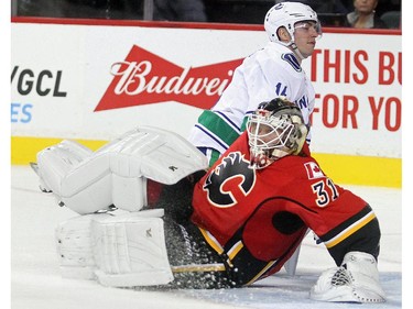 Calgary Flames goalie Karri Ramo is bowled over by Alexander Burrows of the Vancouver Canucks during the second period of the season opener Wednesday October 7, 2015 at the Saddledome. Burrows got a goaltender interference penalty on the play.