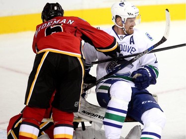 Dennis Wideman of the Calgary Flames knocks down Daniel Sedin of the Vancouver Canucks in front of the Flames net during the third period of the season opener Wednesday October 7, 2015 at the Saddledome.