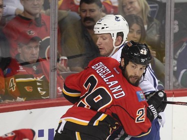 Derek Engelland of the Calgary Flames rams the Derek Dorsett of the Vancouver Canucks into the glass during the third period of the season opener Wednesday October 7, 2015 at the Saddledome.
