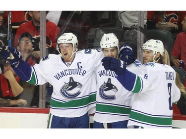 The Vancouver Canucks, from left, Henrik Sedin, Brandon Sutter and Christpher Tanev celebrate a first period goal against the Calgary Flames Wednesday at the Saddledome.  Reader says Canuck fans and the refs irked her.