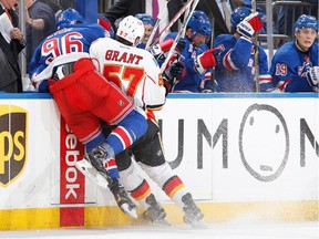 Derek Grant of the Calgary Flames throws a hit against Emerson Etem of the New York Rangers along the boards at Madison Square Garden on Sunday.