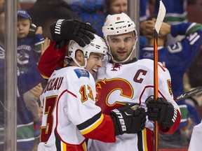 Johnny Gaudreau of the Calgary Flames is congratulated by Mark Giordano after scoring a game-winning goal in overtime against the Vancouver Canucks.