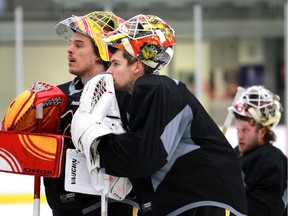 Flames goalies Jonas Hiller, left, Joni Ortio and Karri Ramo listen to the coach as the Calgary Flames took to the ice at WinSport for practice on Monday. Ramo will start on Tuesday against the Washington Capitals.