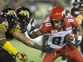 Calgary Stampeders wide receiver Eric Rogers (80) fends off two Hamilton Tiger-Cats during the first half of CFL football action in Hamilton, Ont., on Friday, October 2, 2015.