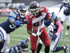 Calgary Stampeders' wide receiver Joe West, centre, (85) evades a tackle by a number of Toronto Argonauts defenders during the first-half of CFL football action in Hamilton, Ont., on Saturday. The Stamps won 27-15.