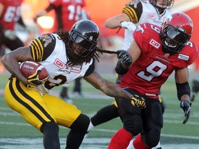 Calgary Stampeders Jon Cornish gives a tug on the Hamilton Tiger-Cats Johnny Sears Jr. during their season opener at McMahon Stadium, on June 26, 2015.