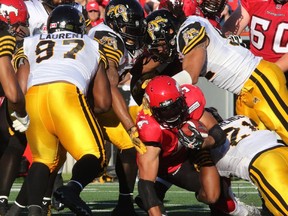 Calgary Stampeders running back Jon Cornish goes against an avalanche of Hamilton Tiger-Cats defenders during the team's home opener in June. In the last meeting between the two teams, Calgary won 24-23.