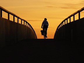 A cyclist rides over a pedestrian bridge across Deerfoot Trail at dusk on Monday Oct. 5, 2015.