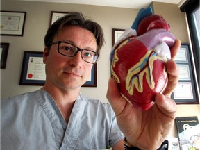 Cardiac Surgeon Dr. Paul Fedak holds up a model of the human heart. Reader says he's grateful for Fedak's top surgical skills.