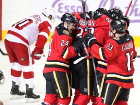 Members of the Calgary Flames, from left, centre Jiri Hudler, centre Sean Monahan, left winger Johnny Gaudreau, defenceman Dennis Wideman, defenceman Mark Giordano and centre Joe Colborne, obscured, celebrated after Colborne scored the tie goal against the Detroit Red Wings during third period NHL action at the Scotiabank Saddledome on October 23, 2015. The Flames broke their home losing streak with the 3-2 overtime win over Detroit.