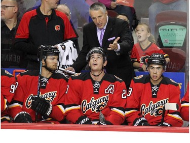 Calgary Flames head coach Bob Hartley gave instructions to players, from left, right winger Michael Frolik, centre Sean Monahan and left winger Johnny Gaudreau during first period NHL action against the Detroit Red Wings at the Scotiabank Saddledome on October 23, 2015. The Flames were looking to break their home game losing streak.