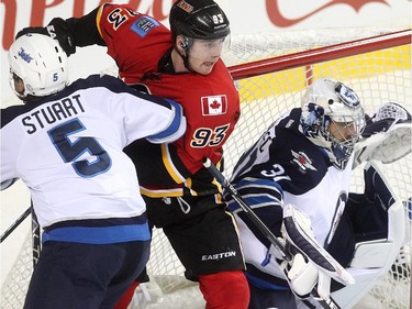 Calgary Flames centre Sam Bennett fought for position against Winnipeg Jets defenceman Mark Stuart outside the crease of Jets goalie Ondrej Pavelec during first period NHL action at the Scotiabank Saddledome on October 3, 2015.